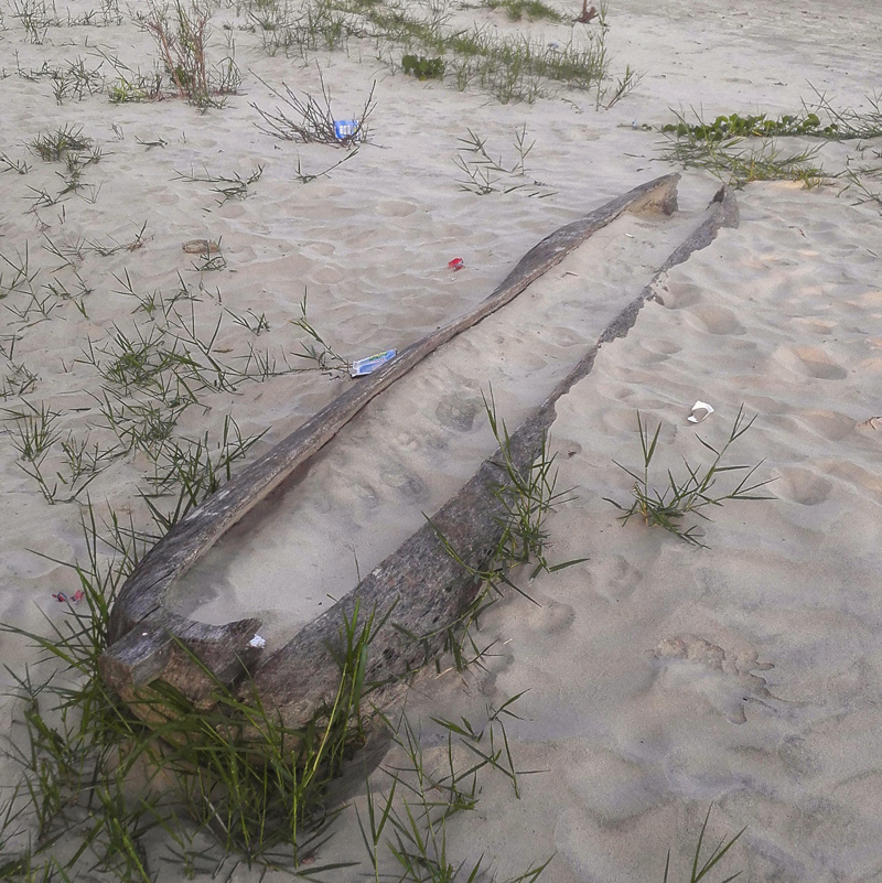 an abandoned canoe buried in sand on thee beach